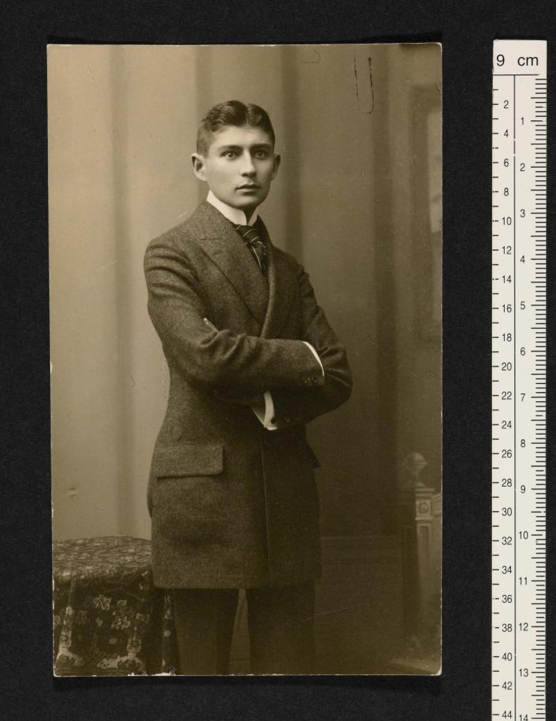 Photo of a young Kafka in a suit with his arms crossed. Photo of a young Kafka in a suit with his arms crossed.